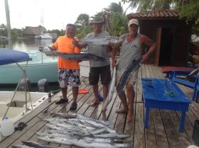 Placencia, Belize, three men holding fish on a dock – Best Places In The World To Retire – International Living